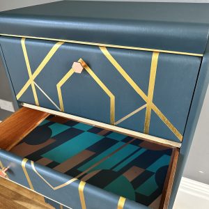 Art Deco cocktail cabinet with petrol blue finish, gold geometric design and patterned interior drawer