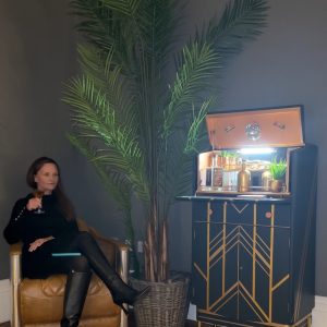 Woman sipping a cocktail in form of a Petrol Blue Art Deco Cocktail Cabinet